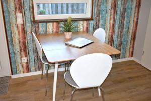 een eettafel met stoelen en een laptop erop bij Lütt Hus an de See Ferienwohnung in Niendorf +6 foto's