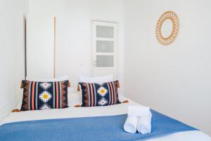 a bedroom with a bed with pillows and a mirror at Viver - Apartamento em Campo de Ourique in Lisbon