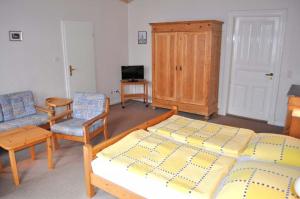 a bedroom with a bed and chairs and a television at Hof Kröger Ferienwohnung Nr 03 in Travemünde