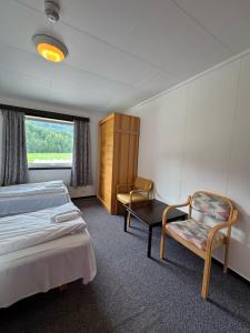 a bedroom with two beds and a chair and a window at Vossestølen Hotel in Vossestrand