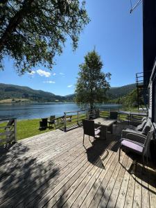 a wooden deck with a table and chairs and a lake at Vossestølen Hotel in Vossestrand