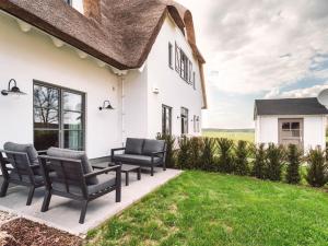 ein weißes Haus mit schwarzen Stühlen und einem Rasen in der Unterkunft Reetidyll am Haff in Stolpe auf Usedom