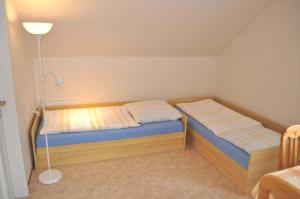 a small bedroom with two beds and a lamp at Hof Kröger Ferienwohnung Nr 04 in Travemünde +5 photos