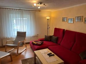 a living room with a red couch and a chair at Ferienwohnung mit Garten und Ostseenähe OVS 111 in Rakow