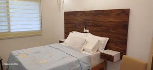 a bedroom with a bed with a wooden headboard at Irina Blessed Homes Bonanjo in Douala