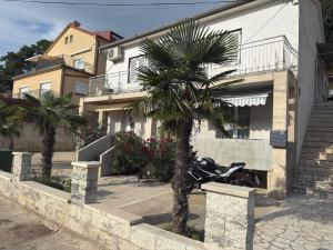 a motorcycle parked in front of a house with a palm tree at Apartments Lollipop in Novi Vinodolski