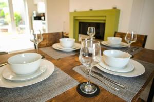 a wooden table with plates and wine glasses on it at Spacious 3 Bedroom Home on South Shields Coast in Westoe