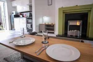 a table with two plates and glasses on it with a fireplace at Spacious 3 Bedroom Home on South Shields Coast in Westoe
