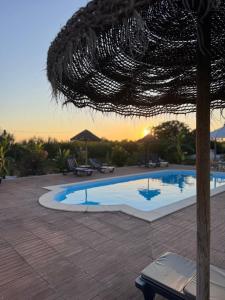 a swimming pool with a sunset in the background at Herdade Da Maridona - Agroturismo in Estremoz