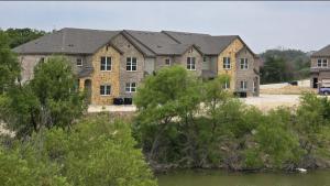 a large brick building with trees in front of it at Landing at Stone Lake Townhomes - Weatherford in Weatherford