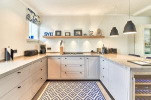 una cucina con armadi bianchi e un tappeto di Ferienhaus Silbermöwe 7b a List