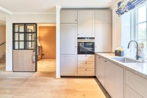 una cucina con mobili bianchi e un frigorifero in acciaio inossidabile di Ferienhaus Silbermöwe 7b a List