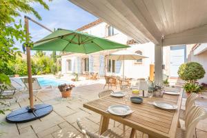 Un patio con una mesa de madera con una sombrilla verde. en Villa Azul - Welkeys, en Bandol