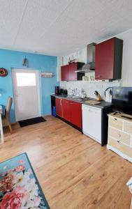 cocina con armarios rojos y blancos y suelo de madera en Kos - Bungalow "Kapitänskajüte ", en Ostseebad Koserow 6 fotos más