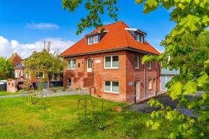 a brick house with an orange roof at Die Zimmerei 4, zentrale Lage, Erdgeschoss mit Terrasse in Greetsiel