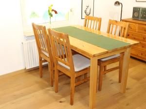 a wooden dining room table with four chairs and a green table at Appartement "Deichblick" - Nordseebad Burhave in Burhave +4 photos