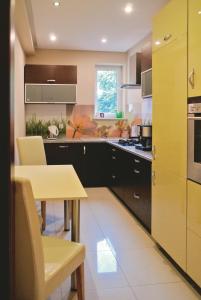 a kitchen with a table and a yellow kitchen at Apartament Rajska in Gdańsk