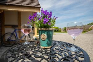 two glasses of wine on a table with flowers at Luxury Holidays Yorkshire - Bancroft Cottage in Bedale +4 photos