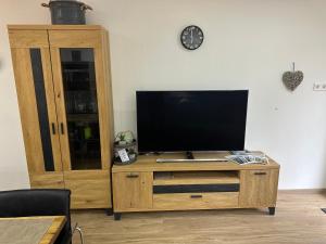 a television on a wooden entertainment center with a clock at FeWo 236 Aparthotel Mittelberg in Mittelberg
