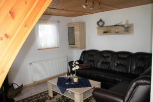 Una sala de estar con un sofá de cuero negro y una mesa. en Rügen Fewo 181, en Wiek auf Rügen