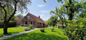 una casa de ladrillo en un patio con césped verde en Nr 150 - Ferienhaus An't Deep, en Neufunnixsiel