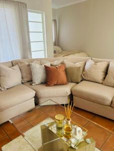 Una sala de estar con un sofá y una mesa de cristal. en Niizala Apartments, en Windhoek