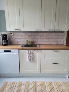 Una cocina con gabinetes blancos y un fregadero. en Villa Haave, en Kotka