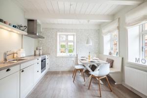a kitchen with white cabinets and a table and chairs at Maries Stuga in Utersum