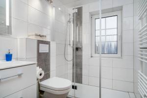une salle de bain blanche avec douche et toilettes dans l'établissement Von Manderley, Ferienhaus mit 3 Schlafzimmern und Garten, Hund willkommen!, à Greetsiel