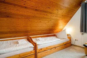 - 2 lits dans une chambre avec un mur en bois dans l'établissement Von Manderley, Ferienhaus mit 3 Schlafzimmern und Garten, Hund willkommen!, à Greetsiel