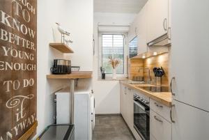 une cuisine avec des armoires blanches et un réfrigérateur blanc dans l'établissement Von Manderley, Ferienhaus mit 3 Schlafzimmern und Garten, Hund willkommen!, à Greetsiel