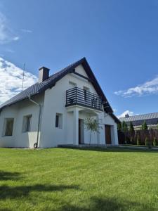 a white house with a lawn in front of it at Przystanek Osłonin- całoroczny dom na wynajem in Osłonin