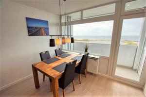 ein Esszimmer mit Tisch und Stühlen und einem großen Fenster in der Unterkunft Ferienpark - Haus C, App 0C1109 in Heiligenhafen