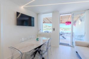 a white dining room with a table and chairs at Princes Apartment PortoCervoBEACH con accesso diretto in spiaggia Piccolo Pevero in Porto Cervo