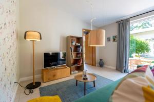 Una sala de estar con un televisor y una mesa. en Haus Silvana, App 03 Bungalow, en Zempin