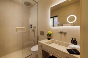un bagno con lavandino, water e specchio di Albergo Botti a Città di Corfù Altre 37 foto