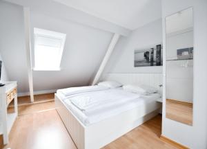 Un dormitorio blanco con una cama y un espejo. en Haus Windhuug Wohnung 5, en Utersum