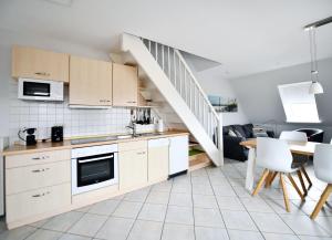 Una cocina con gabinetes blancos y una escalera. en Haus Windhuug Wohnung 5, en Utersum