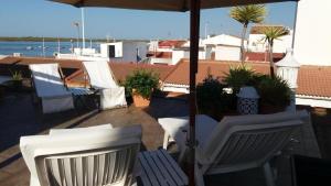 eine Terrasse mit zwei weißen Stühlen und einem Sonnenschirm in der Unterkunft Casa Marinera en El Rompido in El Rompido