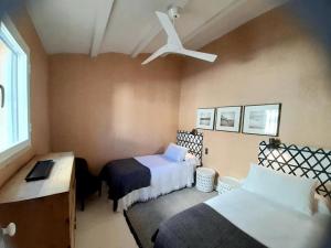 ein Schlafzimmer mit zwei Betten und einem Deckenventilator in der Unterkunft Casa Marinera en El Rompido in El Rompido