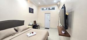 a room with a bed and a television in it at Ease Living Palem Kenari in Jatirarangan