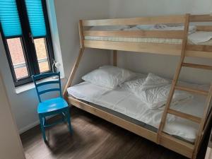 a bedroom with two bunk beds and a blue chair at Fischerdorf No 26 in Heiligenhafen +9 photos