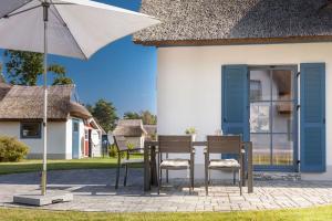 a table with chairs and an umbrella in front of a house at Dünenbraut in Glowe