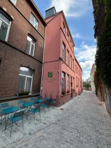 根特Flandria Hotel Gent Centrum的一条在粉红色建筑前的街道上,有桌椅