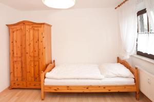 a bedroom with a bed and a wooden cabinet at Ferienwohnung Birkenstraße Nesselwang 9 in Nesselwang +4 photos