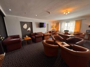ein Wartezimmer mit braunen Ledersesseln und -tischen und ein Wartezimmer in der Unterkunft Ashley Court Hotel in Andover