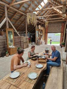 a group of people sitting around a wooden table at Zemnieku saimniecība Paldaži in Limbaži +3 photos
