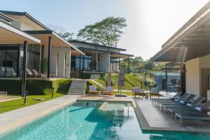 a swimming pool with lounge chairs and a house at Epic Tamarindo Boutique Hotel in Tamarindo