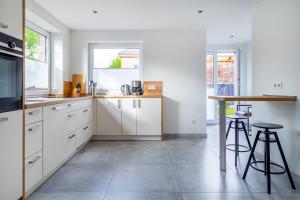 a kitchen with white cabinets and a counter with stools at Die Zimmerei 1, zentrale Lage, Erdgeschoss mit Terrasse, Hund willkommen! in Greetsiel