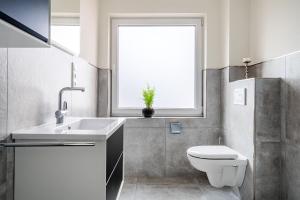 a bathroom with a toilet and a sink and a window at Die Zimmerei 2, zentrale Lage, Obergeschoss mit Terrasse in Greetsiel